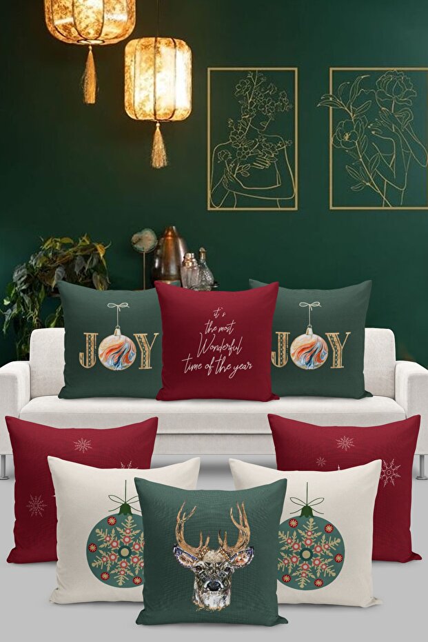 Decorative pillows with festive designs on a white sofa against a green wall with framed artwork.