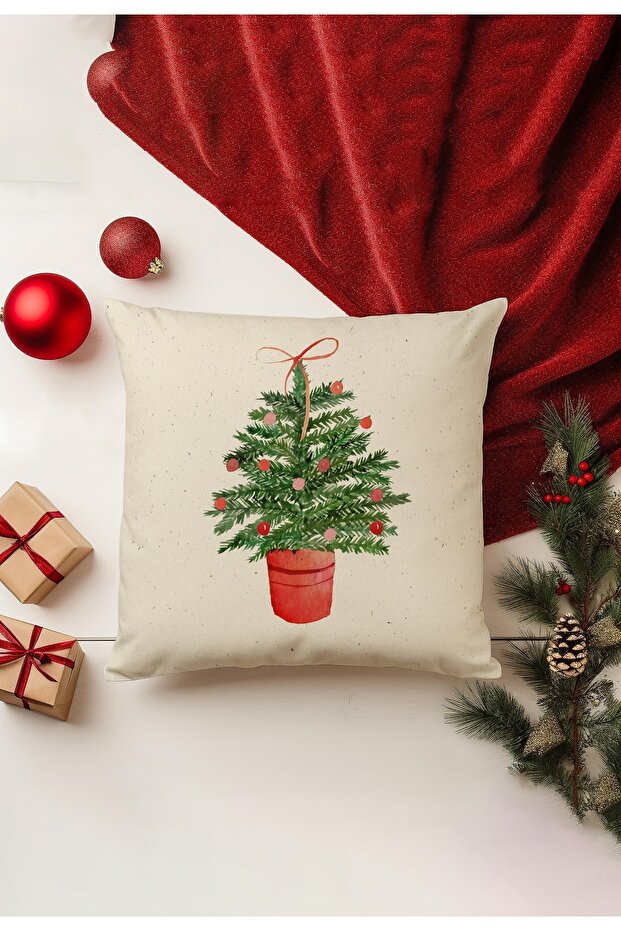 Decorative pillow with Christmas tree design on a white surface with red fabric and ornaments.