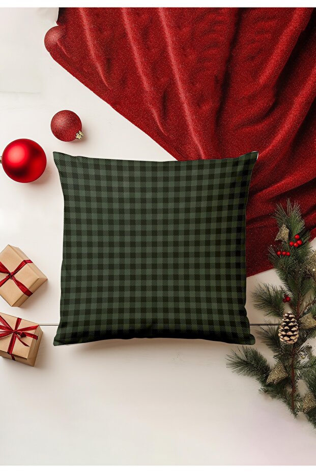 Green checkered pillow on a white surface with Christmas decorations including red ornaments and a tree.