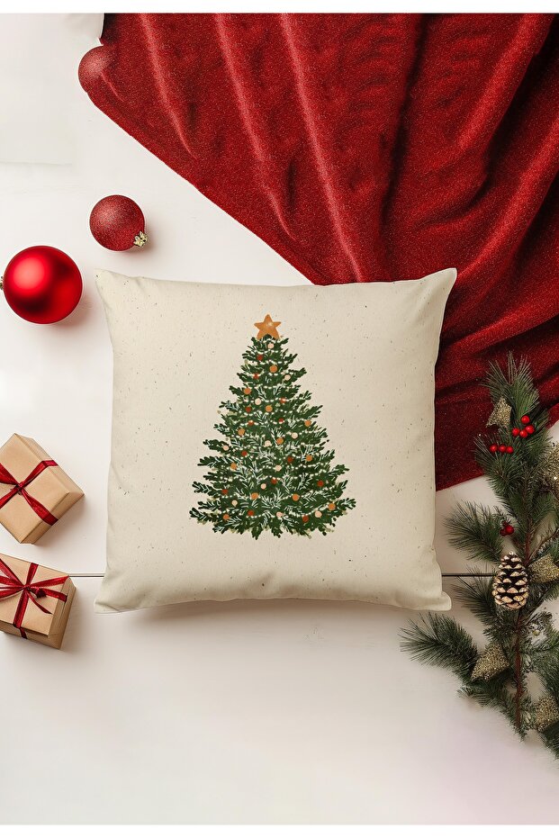 Decorative pillow with Christmas tree design on a white surface with red blanket and ornaments.